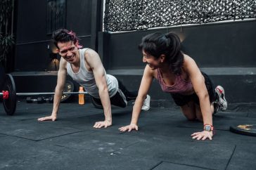 Man and woman doing pushups while smiling during a workout inside a Mexico City gym.